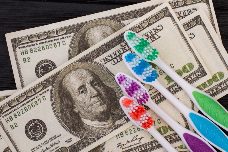 Close up of money and toothbrush. American dollars and colorful toothbrush.